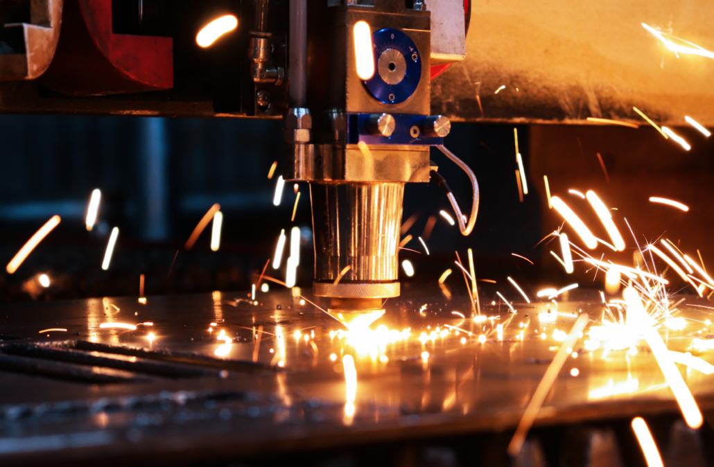 Industrial laser cuts a thick sheet of metal. Molten metal scatters in all directions